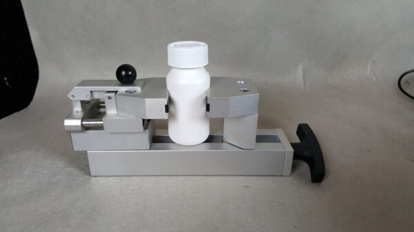 Laboratory bottle clamped in testing machine.
