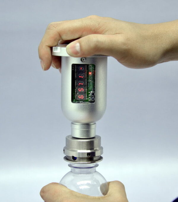 Hand using digital torque meter on bottle cap.